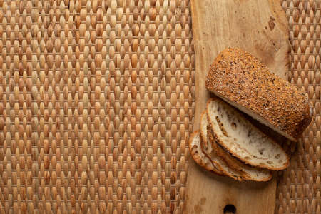 Cut bread showing air texture of flour on wood block with weave background and copy space.の写真素材