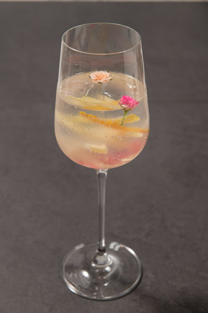 Cocktail with lemon and pink flower in a glass on black backgroundの写真素材