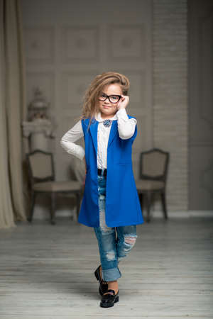 beautiful girl with glasses is standing on the stairs in the blue dress and jeansの写真素材