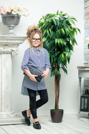 beautiful girl in glasses stands next to a flower in a potの写真素材