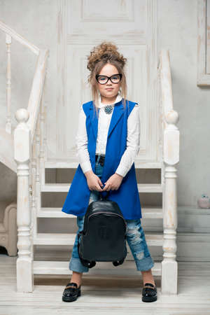 beautiful girl with glasses is standing on the stairs in the blue dress and jeansの写真素材