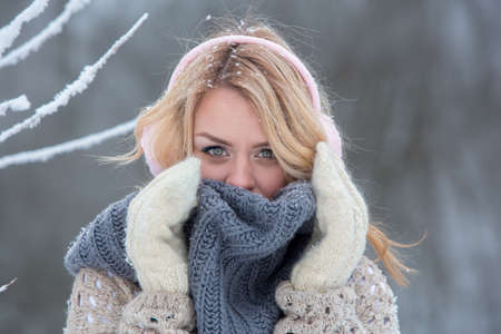 Beautiful girl in pink headphones on the scarf with snow goの写真素材