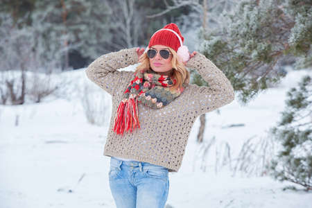 Beautiful girl in a red hat and sweater in the snow in pink with headphonesの写真素材