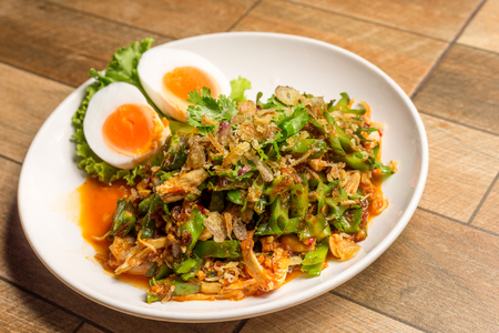 Wing Bean Shrimp Salad with boiled egg on white dish on wood table.の写真素材