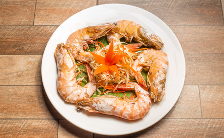 Steamed seafood or Steamed shrimp with herbs and vegetable in white dish on wood table.の写真素材