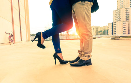 Lovers couple on date kissing and hugging on urban background at sunrise - Man and woman legs...