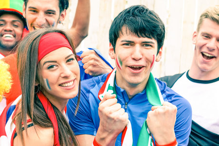 Sport supporter cheering at football stadium together with many multiracial fans - Young man at...