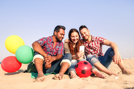Cheerful multiracial group of friends taking selfie on the beach - Couple and indian race guy using...