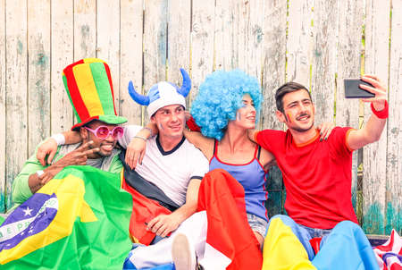 Group of mixed supporter taking selfie outside football stadium - Football fans self photo against violence and unrest at sports event - Concept of friendship and fun together - Focus on female faceの写真素材