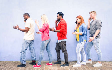 Multiracial row of young people using mobile phone walking on urban street - Teenagers queue talking at cell outdoor on blue background - Concept of addictiont to technology - Focus on red hair girlの写真素材