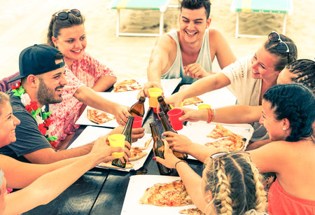 Group of best friends toasting with beers at cafe bar restaurant - Teenagers having fun eating pizza...