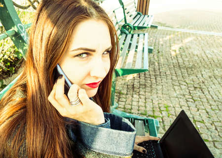 Young woman making emergency phone call from urban park - Concept of plea for help and outdoors harassmentの写真素材