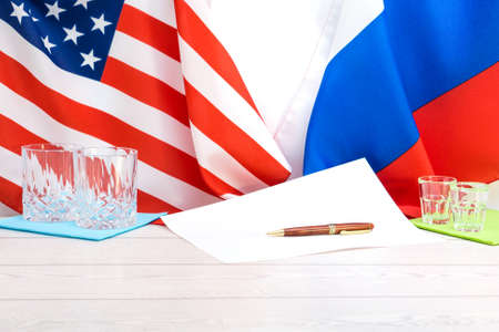 American and Russian flags on agreement table with ballpoint pen and signing papers  - Political concept of peace cooperation and business between world powerful countries - White copy spaceの写真素材