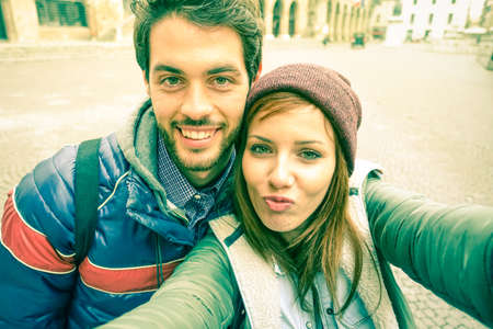 Young couple taking selfie by mobile phone in old city - Students teenager having fun with funny face expression for self photo with smartphone - Concept of joy and  memories vintage cold tones filterの写真素材