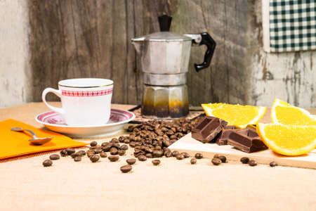 Rustic breakfast table with chocolate bar coffee beans mocha and sliced orange - View of vintage style kitchen with natural energy giving food on old wooden background - Concept of retro lifestyleの写真素材