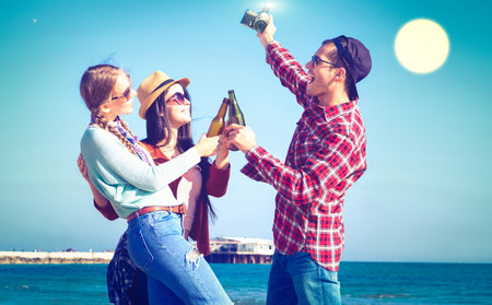 Friends happy moments drinking beer at beach full moon night party - Joyful students having fun...