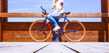 Two wheeler commuter standing on wooden footbridge with sport bike - Woman riding bicycle at...
