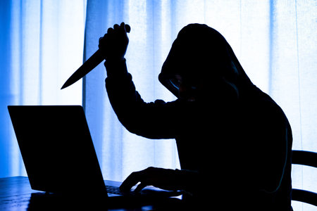 Hooded dark man at pc brandishing knife with a threatening attitude - Dangerous cyber stalker...