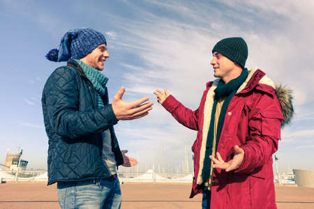 Men models wearing winter clothes using gesturing in friendly discussion - Best male friends are hugging - Trendy students having fun outdoor in sunny day - Concept of friendship happiness and youthの写真素材