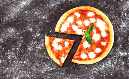 Pizza Margarita on black board dusted 
 with flour top view image - Traditional italian Margherita with basil and fresh mozzarella cheese on dark backgroundの写真素材