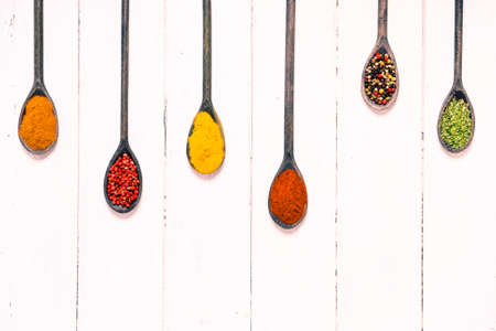 Assorted spices in old wooden spoons top view on white wood background vertical lines - Colorful aromatic food ingredients on rustic kitchen table with copy space above imageの写真素材