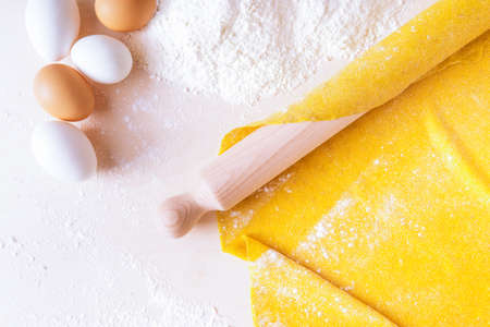 Rolling pin with puff pastry eggs and flour flat lay top view image - Homemade italian pasta preparation with natural ingredients on wooden board with copy spaceの写真素材