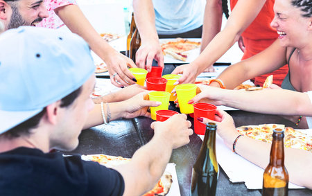 Happy friends toasting at pizza party day outdoor -  Young people hands circle holding drinks and...