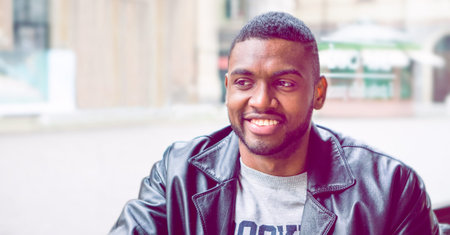 Handsome african american young man smiling - Close-up portrait of black attractive male in confident attitude looking aside  sitting inside cafe bar- Dark cinematic filterの写真素材
