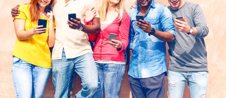Teenagers texting mobile phone messages row on pink background - Multiracial friends holding smartphone smiling - Multicultural teens generation using cellphone - Modern communication concept - Imageの写真素材