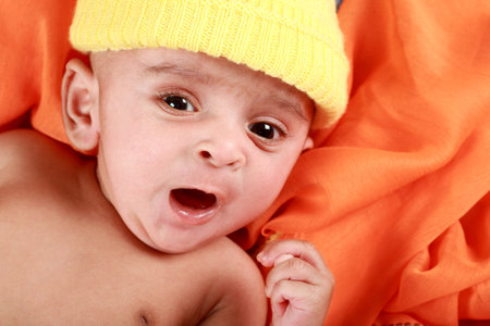 Yawning Baby with a Yellow Hat on Orange background