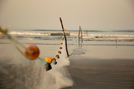Long fishing net arranged with the help of wooden sticks on a beach in Indiaの写真素材