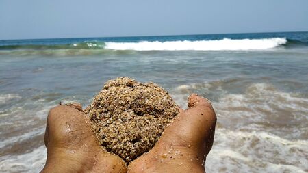 Photo of hands with a ball of sand at a beach in Indiaの写真素材