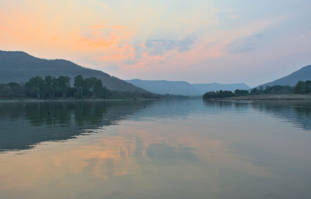 Panoramic landscape view of beautiful Rihegaon Dam with flowing water, clouds, and lush green...