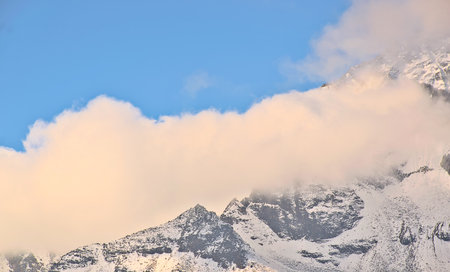 Panoramic landscape view of the majestic snowcapped Himalayas mountains with dense clouds in winter. Photo clicked at Zero Point or Yumesamdong, a famous tourist place in North Sikkim, Sikkim, Indiaの写真素材