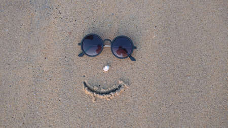 A decorated face drawn using sun glass and shell on the beachの写真素材