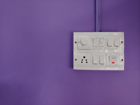 A white switch board on a violet painted wallの写真素材