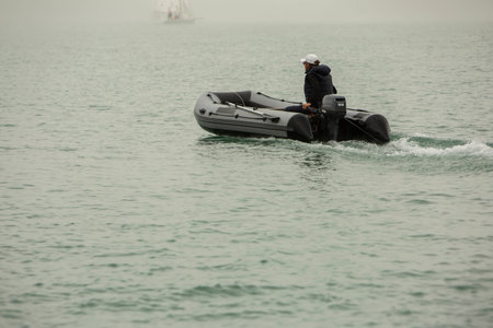 man in an inflatable boat floats on water in foggy weather