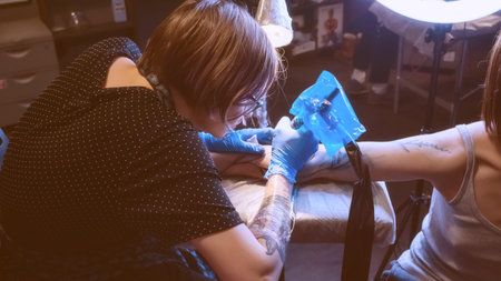 Tattoo artist make tattoo in studio, tattooing on the body. Floral tattoo