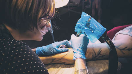Tattoo artist make tattoo in studio, tattooing on the body. Floral tattooの写真素材