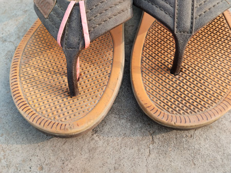 old grungy torn slippers on dirty floor, used torn slippers or torn sandals. broken sandals after long term usageの写真素材