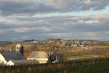 On a cold, winter day, on a hilly rise, looking down at a neat looking farming community, buildings...
