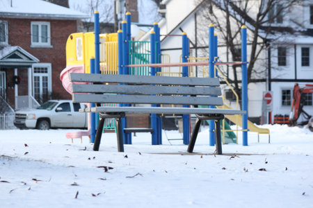 Vacant park bench in a snow filled park during the winter season.