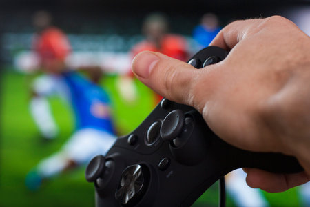 playing soccer on a front of big monitor with black gamepad