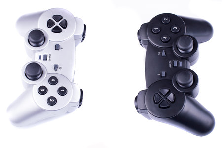 silver and black gamepads oposite each other isolated on a white