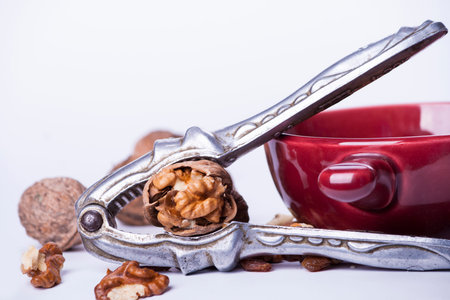 wallnuts, nutcracker and plate with shelled nuts on white background