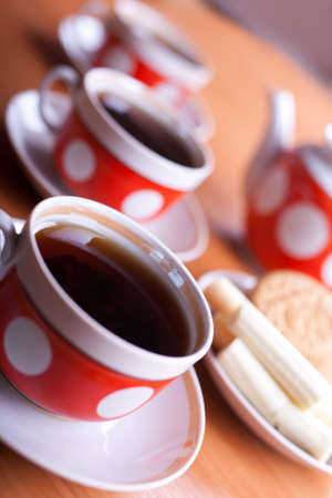 three cups of black tea and teapot on a tableの写真素材