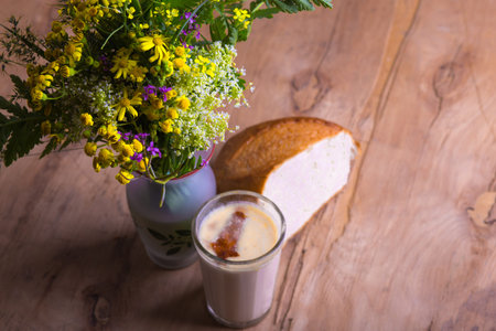 bouquet of wildflowers with glass of ryazhenka and bread on a table