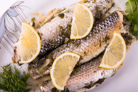 three fried fishes with slices of lemon on a plateの写真素材