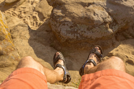 men's foots hangs down from a roc k on a desert 