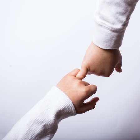children's hands hold each other's little fingers in a sign of reconciliationの写真素材